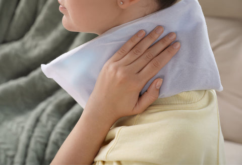 Woman holding an ice or a heat pack to her neck. Pinched neck nerves are a potential cause of shoulder pain with no injuy