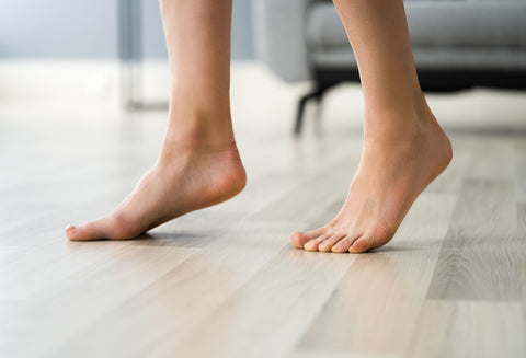 woman walking across a hardwood floor on the balls of her feet, a good exercise for flat feet 