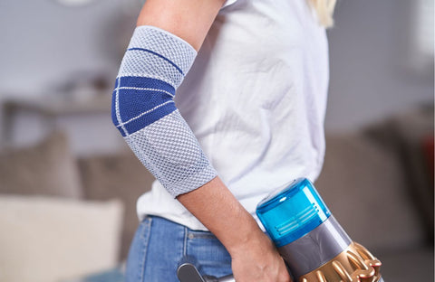 Close up of EpiTrain Elbow Brace as woman vacuums while wearing it.