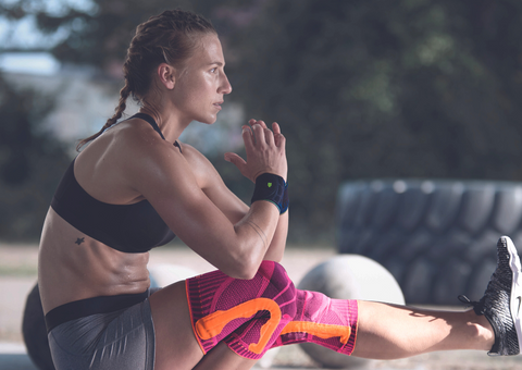 Woman wearing black weightlifting wrist straps doing squats 