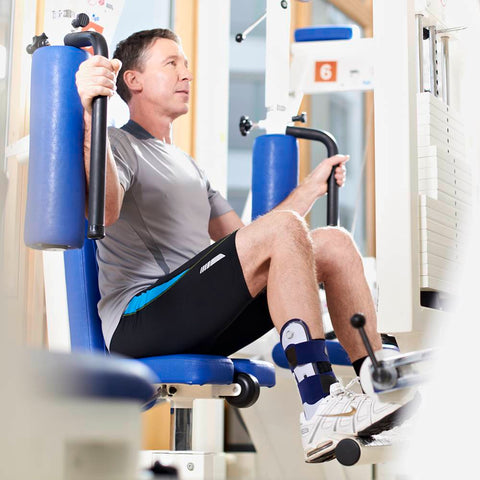 Man exercising in the gym wearing a Bauerfeind ankle brace for a sprained ankle