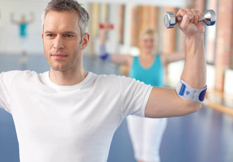 Man in gym wearing a Bauerfeind elbow strap to improve his tennis elbow