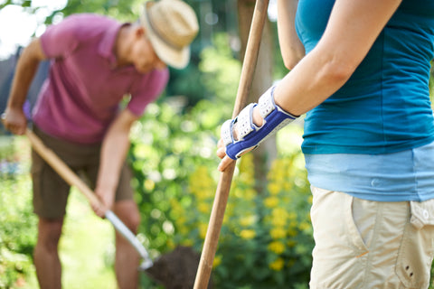 Woman gardening with her husband. The shot focuses on the ManuLoc wrist brace she's wearing, a good way to stop the wrist hurting from carpal tunnel syndrome