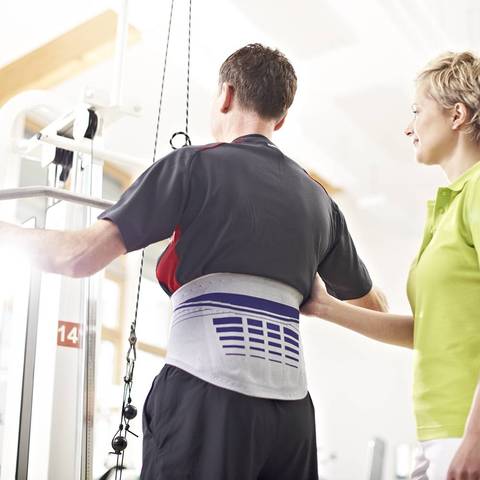 Person exercising in a gym wearing a Bauerfeind lower back brace for relieve pain