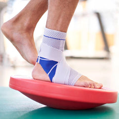 Wearing a Bauerfeind ankle brace while doing a balancing exercise on an unstable surface to improve balance after ankle injury.