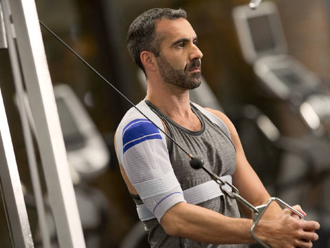 Man doing shoulder exercises at the gym in an OmoTrain shoulder brace