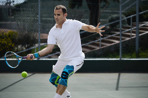 Action shot of a tennis player about to hit the ball. He wearing Bauerfeind's Sports Knee Supports, which protect the knees from injuries like patellar tendonitis