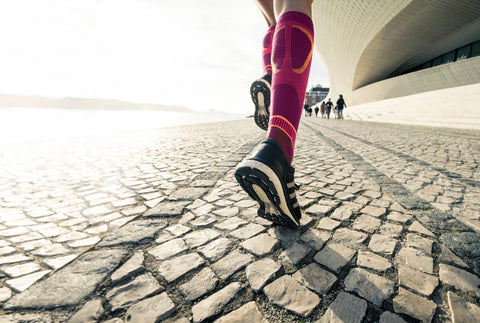 Shot of a woman's lower legs as she runs down the street. She's wearing Bauerfeind Performance Socks, which have graduated compression to reduce muscle oscillation.