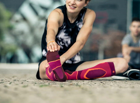 Woman stretching her hamstrings while wearing a pair of Bauerfeind's Performance Socks, a great pick for soccer players