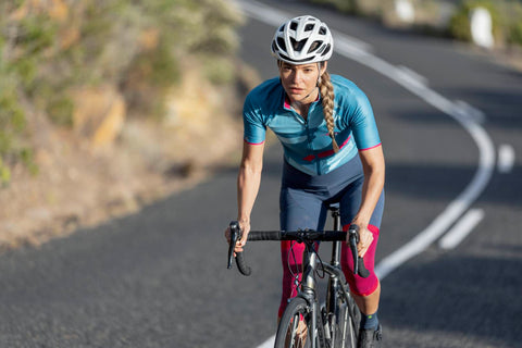 Woman cyling in Bauerfeind's Sports Compression Knee Support. To improve her cycling speed, however, she'll need to improve her form.