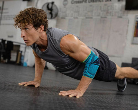 Man doing push ups in Bauerfeind's Sports Elbow Support. Both are good for protecting the elbow from injury in cricket