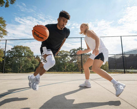 Basketball players playing a game. One of them is wearing Bauerfeind's Sports Compression Knee Support