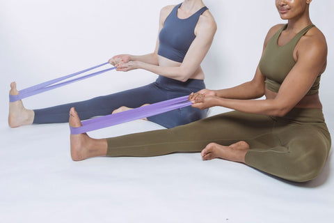 Women sitting on the floor doing ankle strengthening exercises with a resistance band