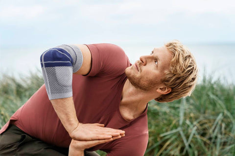 Man doing stretches before gold. He is wearing the EpiTrain Elbow Brace to avoid a golf elbow injury.