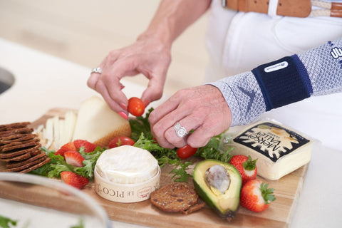 Woman rearranging vegetables on her cutting board. It is a close up of her hands as she works while wearing the ManuTrain Wrist Brace