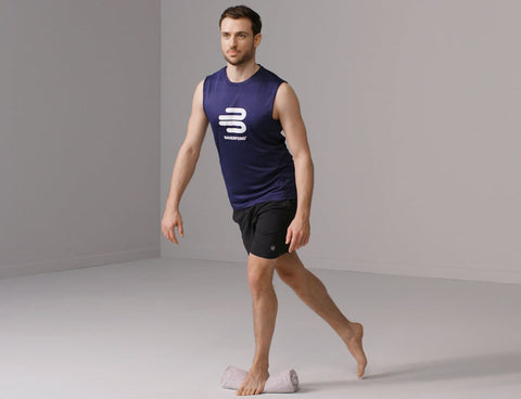 Man in a purple shirt doing the single leg scissor stand exercise for improving proprioception and reducing pain in the knee
