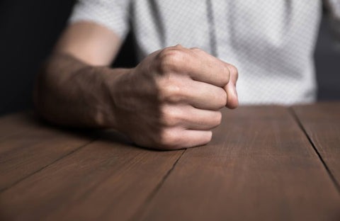 Person sitting at a desk clenching their fist, a good exercise for wrist arthritis