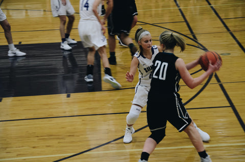 A women's basketball game. One side is wearing black uniforms and the other white.