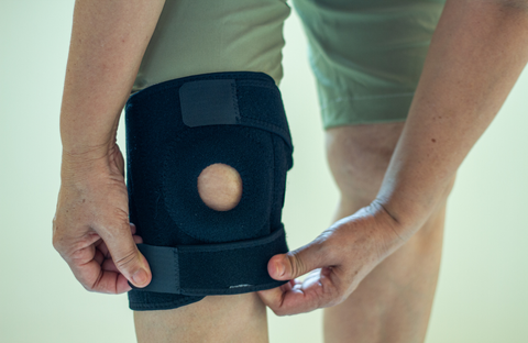 Person putting on and trying to adjust an ill-fitting neoprene knee brace
