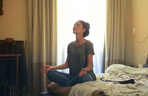 woman meditating on the bed, a good way to reduce perception of pain