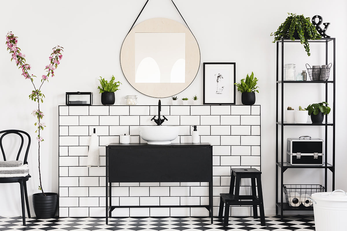 White bathroom with bold checker floor pattern, black cabinet, shelving, chairs, and other accents.