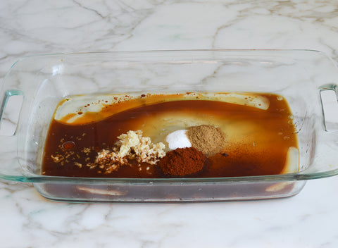Image of the soy sauce, lime juice, vegetable oil, sugar, cumin, chili powder, and garlic placed in a rectangular glass pyrex dish for the oven.