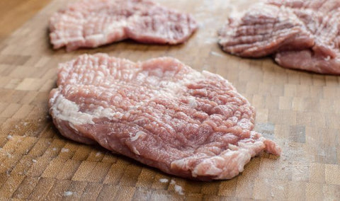 Image of 3 raw, tenderized pork chops.