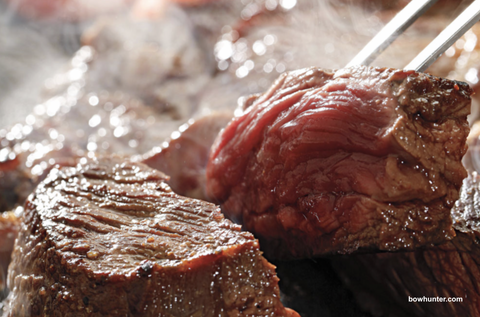 Image of medium rare venison steak still being cooked.