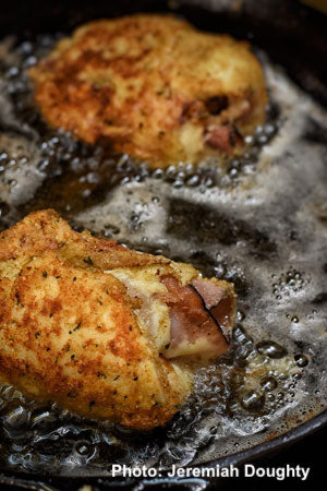 Image of 2 wild turkey cordon bleu cutlets frying in a frying pan.