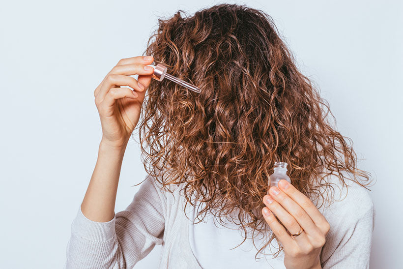 applying serum to curly hair ends