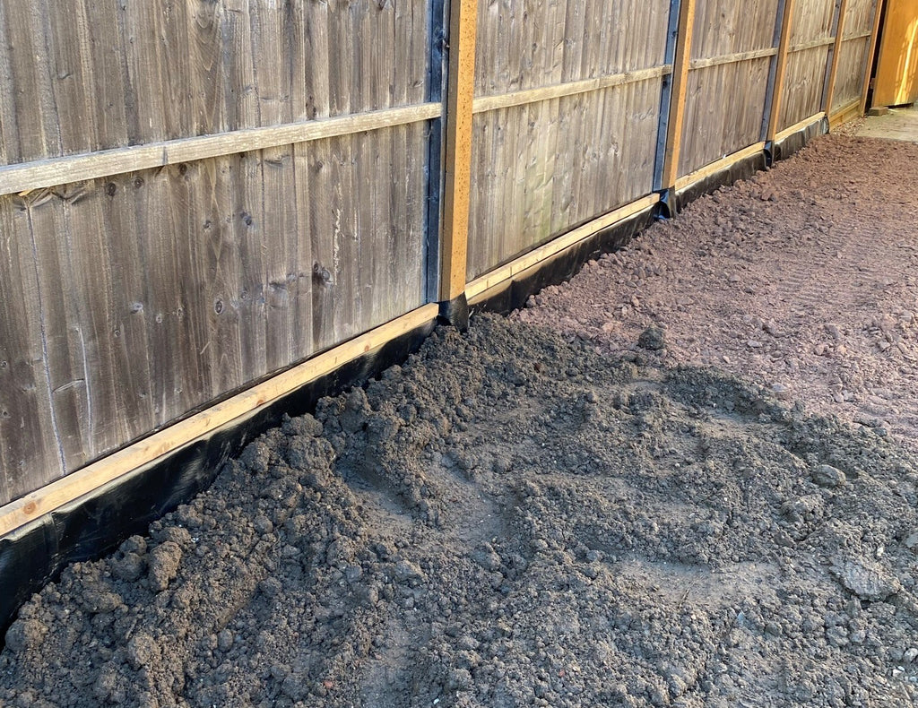 Image of bamboo root barrier installed next to a fence with the trench backfilled.