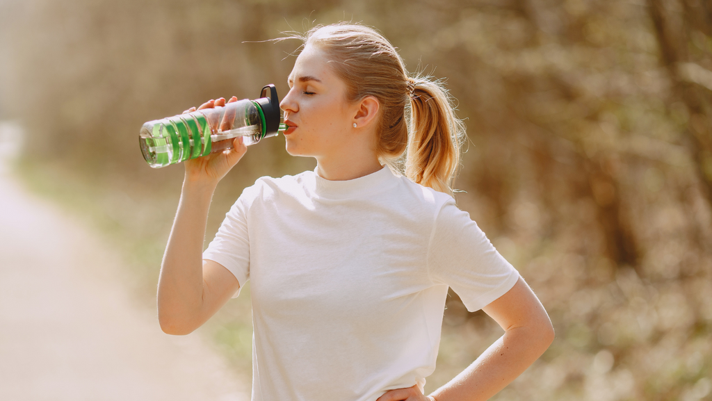 woman staying hydrated with a reusable water bottle