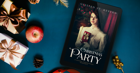 The Christmas Party on an e-reader, laying on a blue surface with apples and Christmas parcels and decorations scattered around.