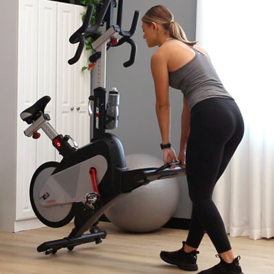 Photo of a woman moving her studio cycle into the storage postiiton