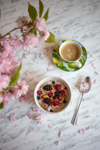 A coffee cup next to a cereal bowl containing berries