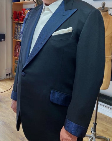 Man wearing a black dinner jacket with navy moire silk facing. 