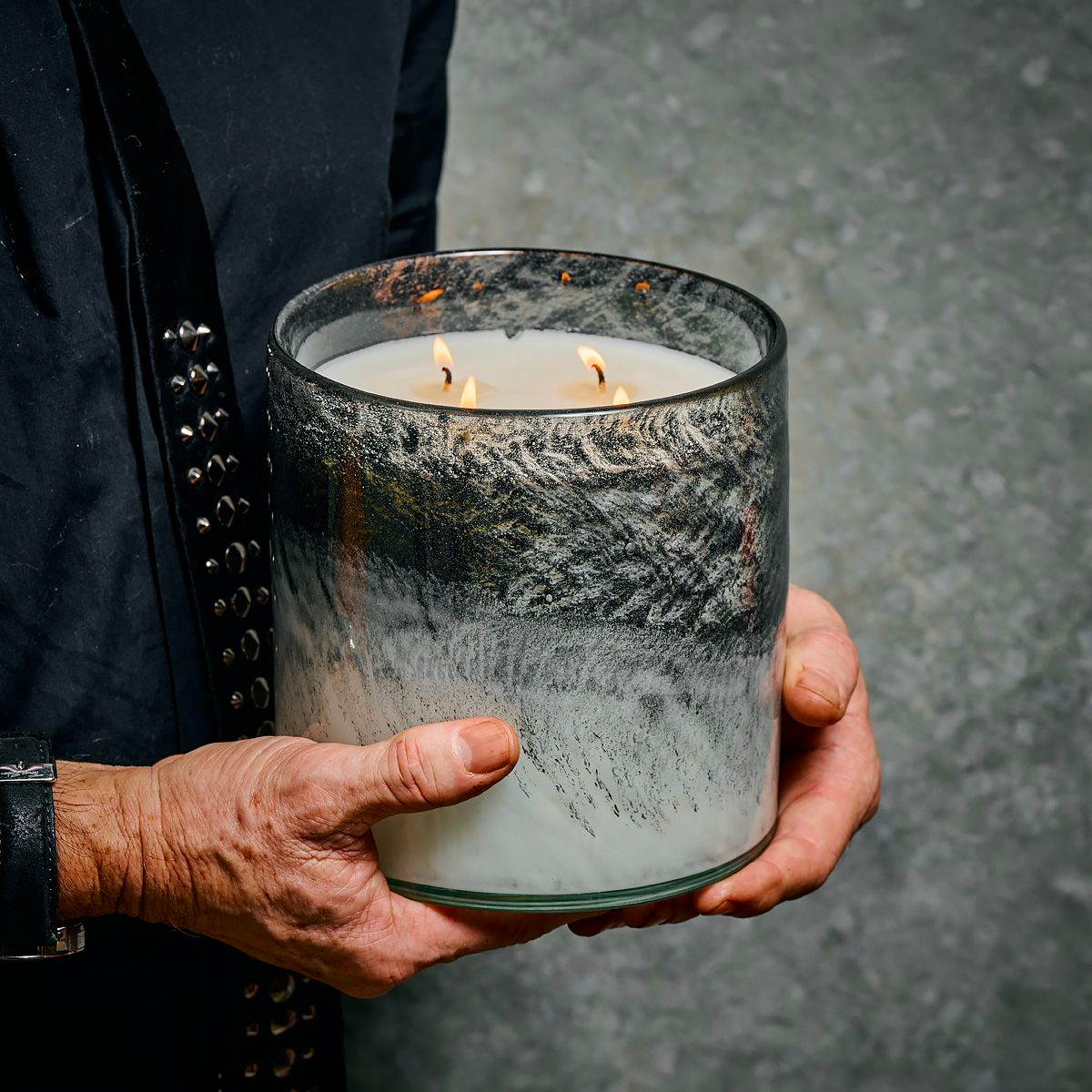 older man holding smokey, rustic looking candle