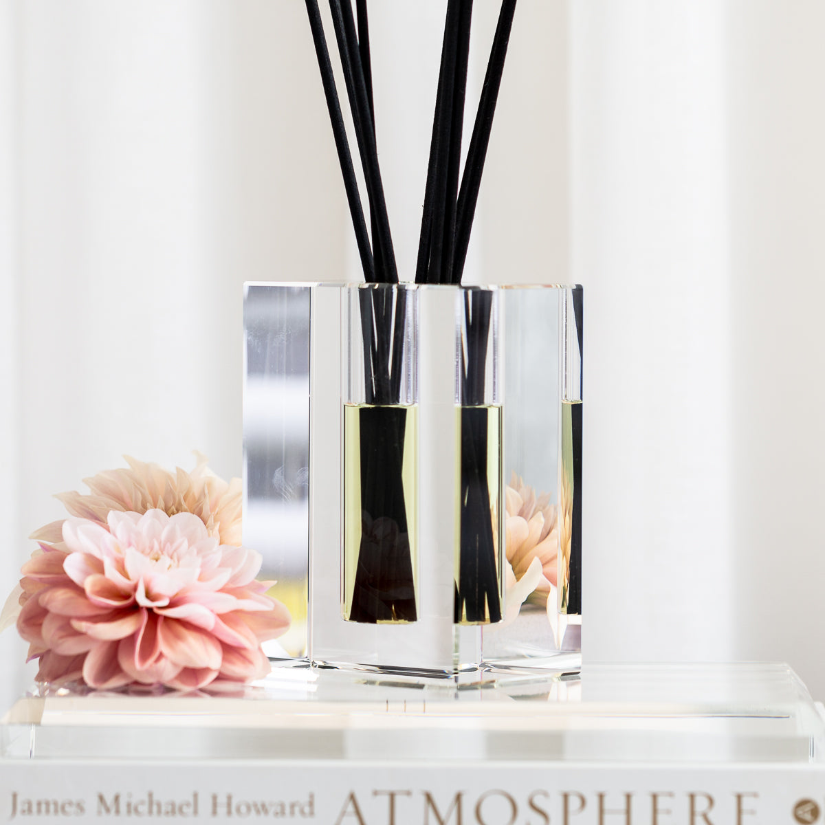 crystal diffuser with black sticks resting on a book about atmosphere 