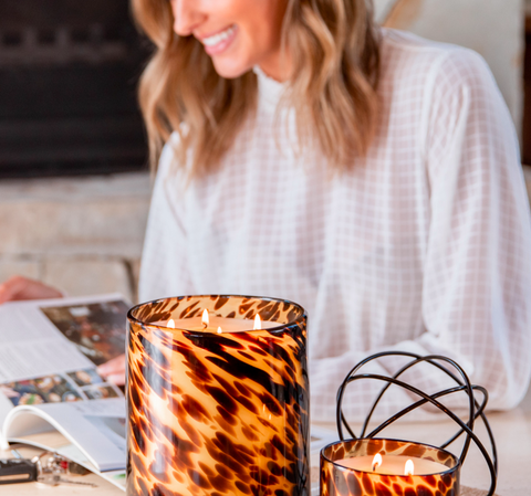 candles on desk with woman reading book in background