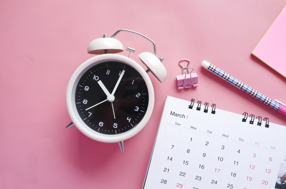 clock and calendar on pink desk