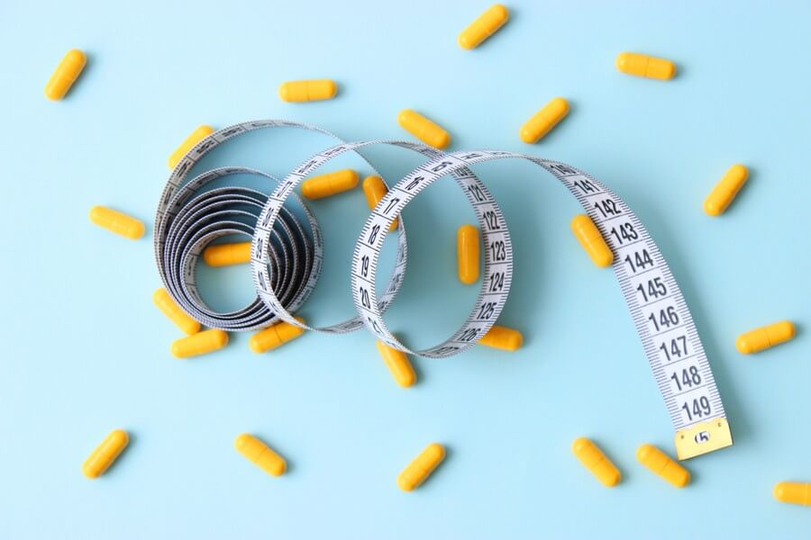 An image showing a tape measure and fat burner pills