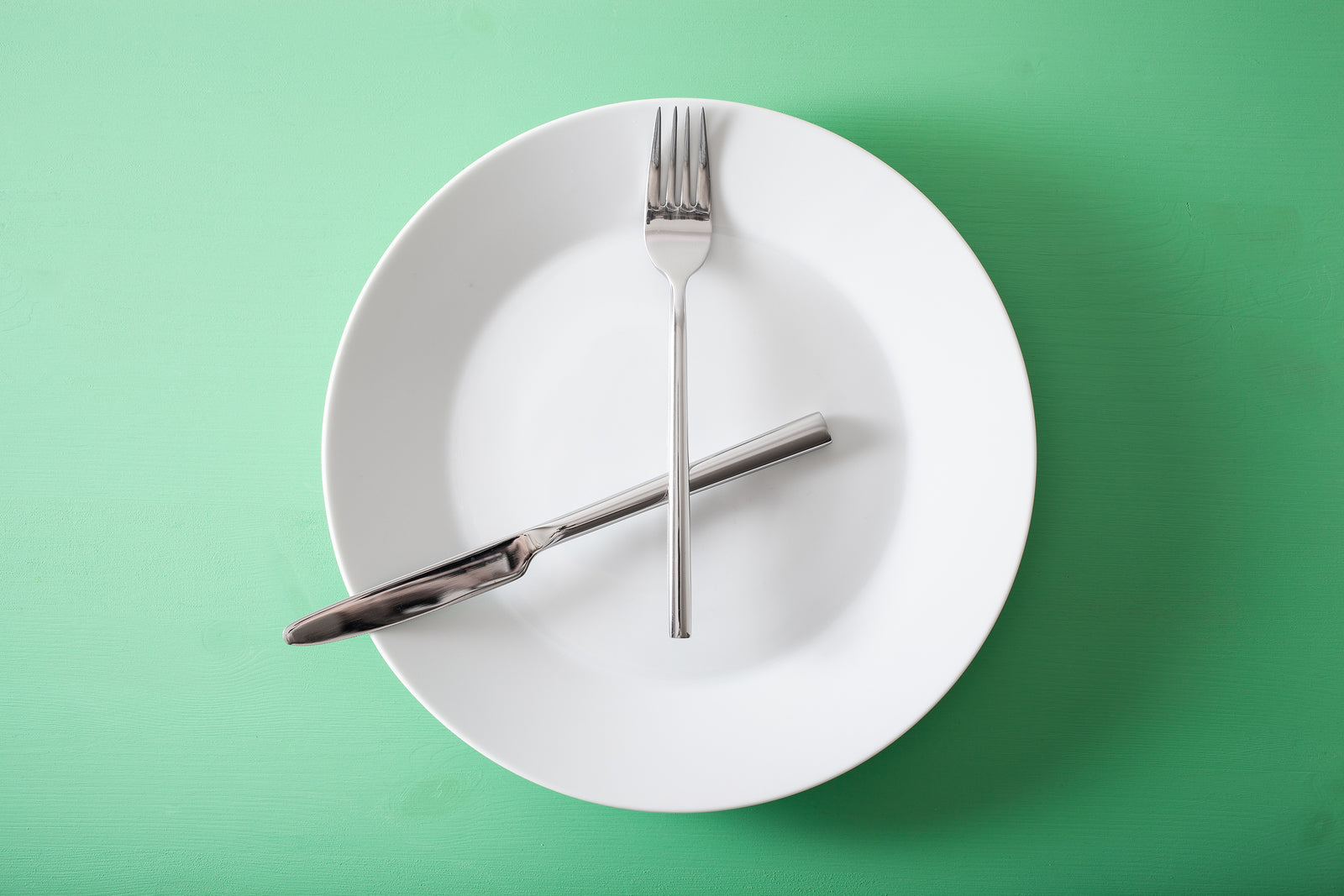 A plate with a knife and fork in the shape of a clock to signify intermittent fasting