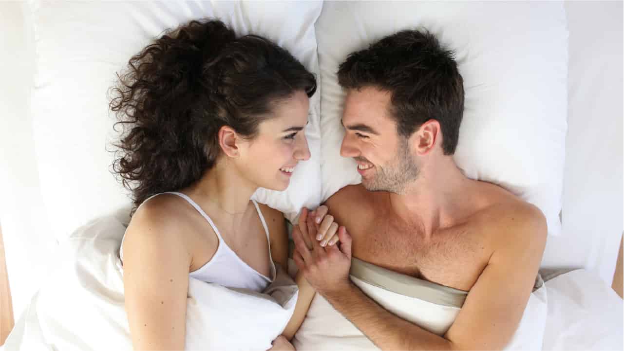 Happy couple lying in bed. One of the health benefits of turmeric is that it may support male libido