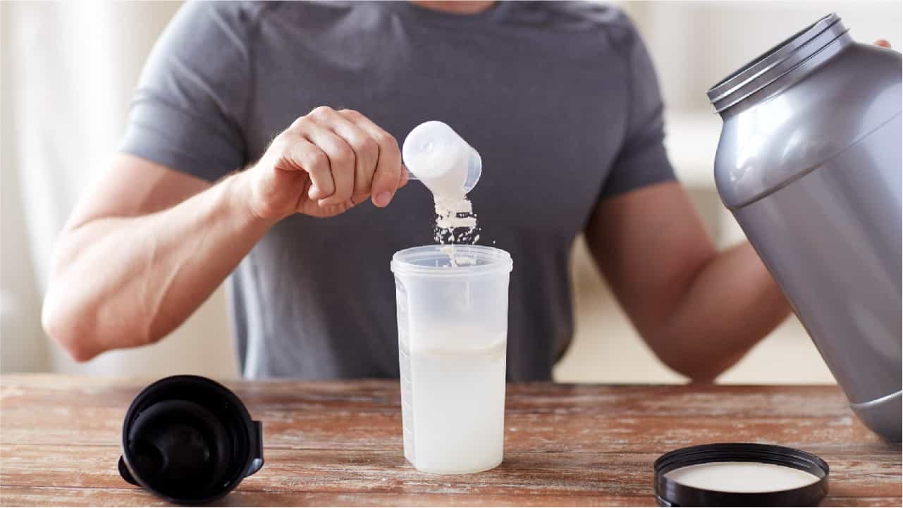 Man measuring out his pre workout creatine supplement: 'creatine monohydrate'