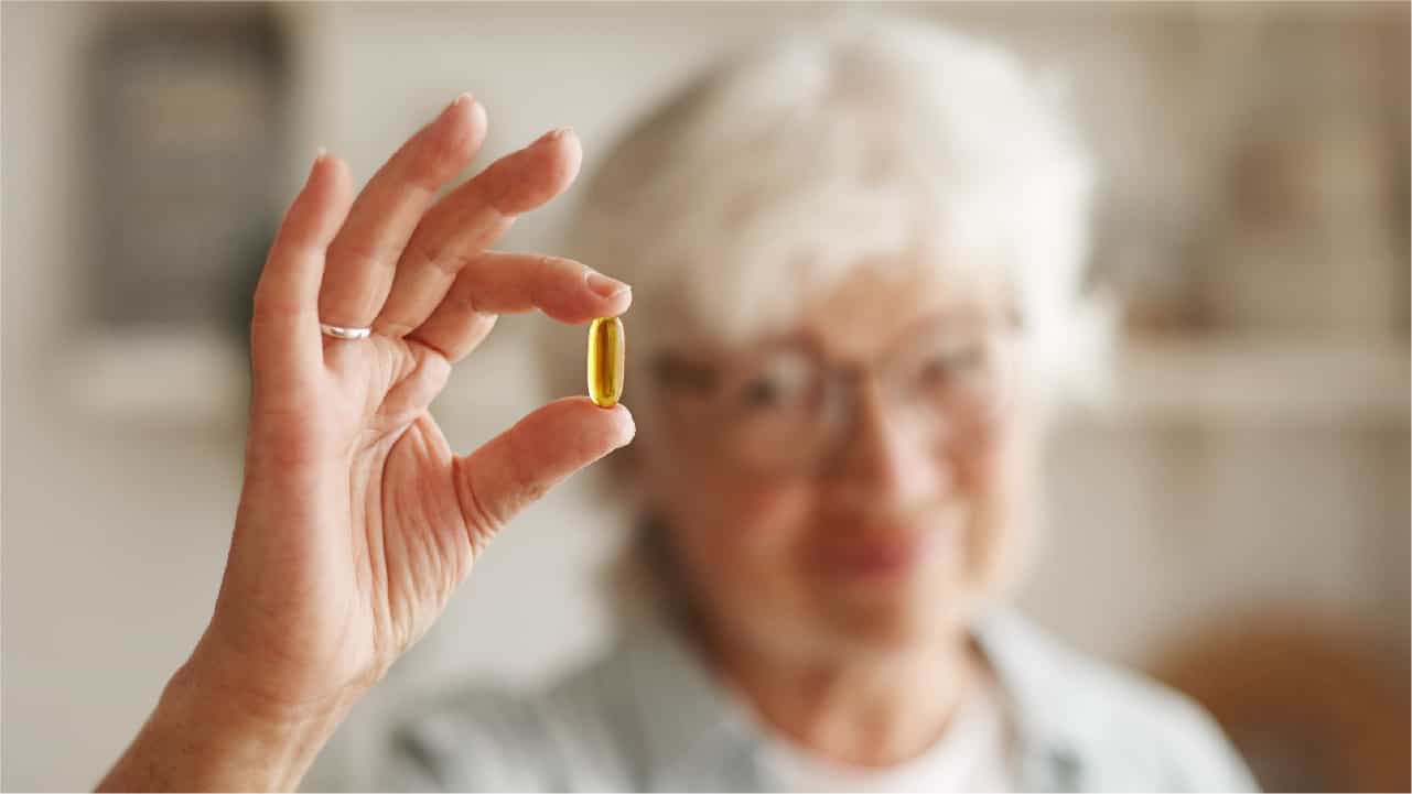 Elderly woman holding a fish oil capsule