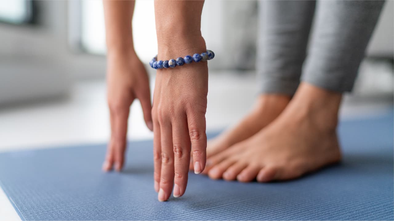 Woman stretching on a yoga mat wearing a bracelet