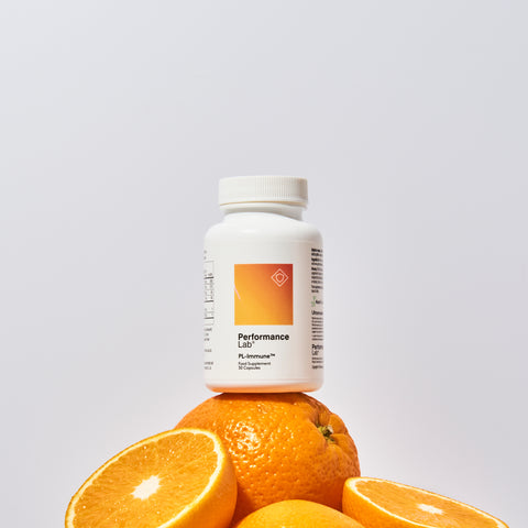 Bottle of Performance Lab Immune supplement on top of a stack of oranges.