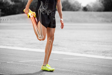 Man stretching with shorts and trainers on, and an outline of his leg bones highlighted under his skin. 