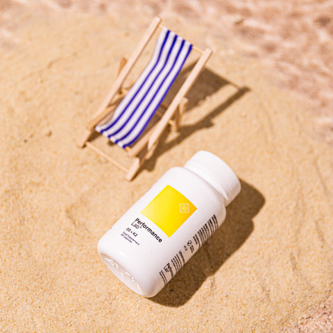 A bottle of Vitamin D supplements on a beach next to a tiny deckchair.