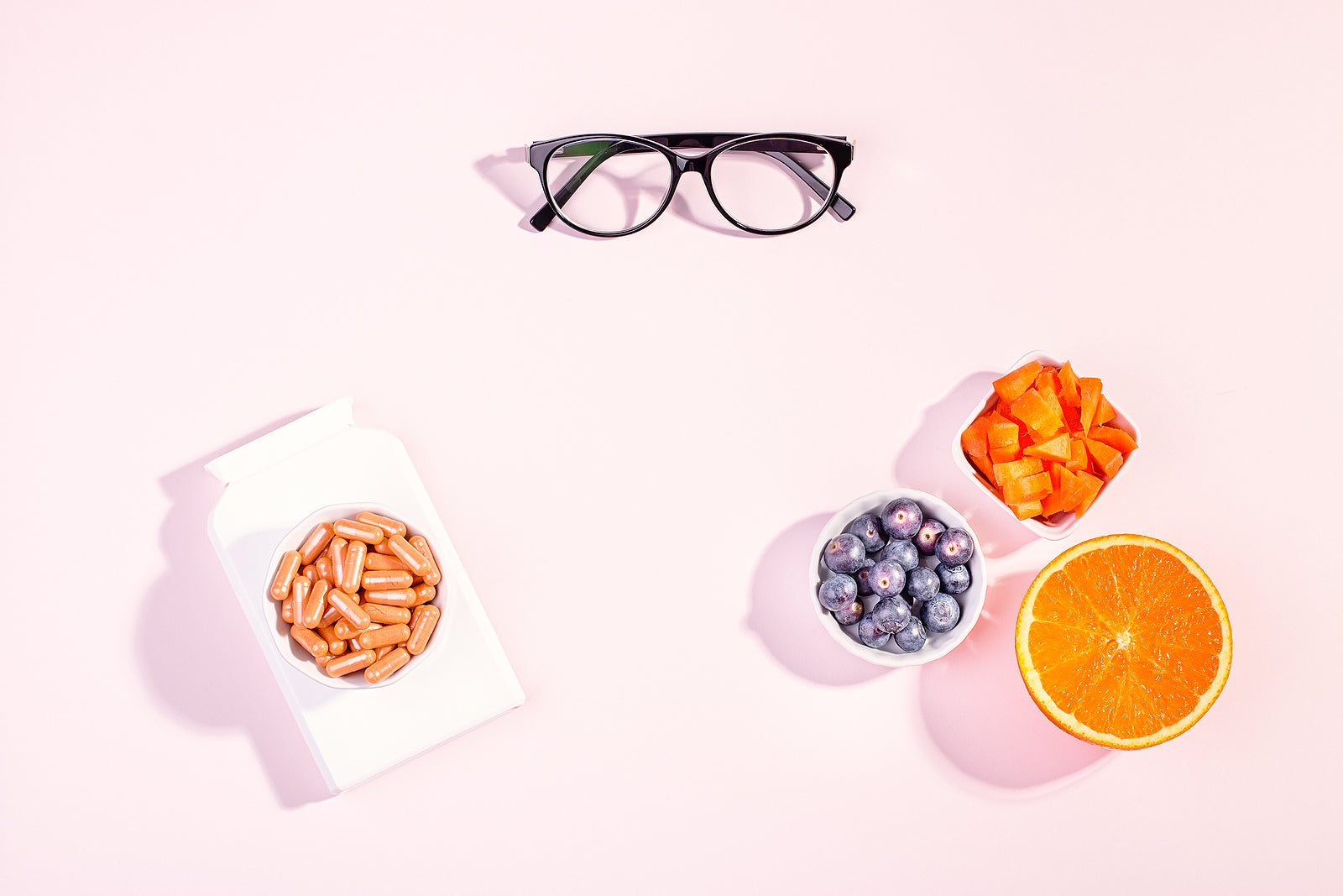 Glasses, supplement capsules and vitamin A sources on a white background